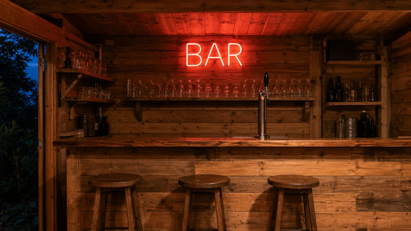 A red neon BAR sign over the finished bar